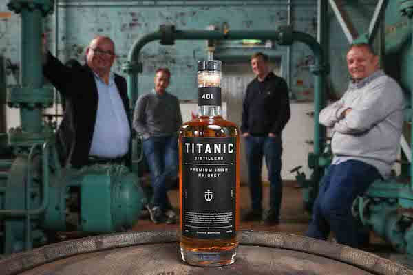 men standing behind a bottle of whiskey Titanic Distillers